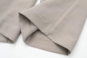 Detail view of khaki trousers hem showing precise stitching and high-quality fabric texture