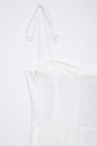 Detailed side view of white cotton dress featuring smocked back and invisible side zipper