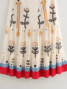 Detail of bohemian floral print dress with tiered hem and colorful striped borders