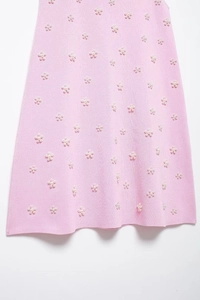 Détail du tissu en maille rose orné de fleurs en perles artificielles blanches