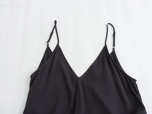 Detail of the deep V-neck and adjustable thin straps on this black satin camisole top