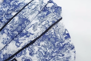 Detail of blue Toile de Jouy printed quilted jacket with dark blue piping and texture