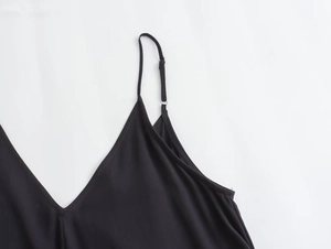 Detail of the V-neckline and adjustable slim shoulder straps on the black midi dress