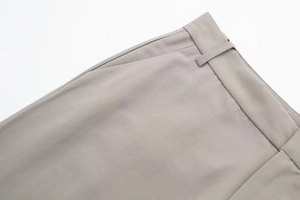 Detail of waistline, belt loops and side pockets on light beige tailored trousers