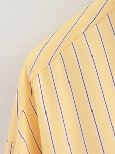 Detailed close-up of yellow striped fabric texture and sewing quality on a loose shirt