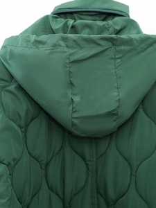 Dettaglio delle cuciture trapuntate a onde e cerniera sul cappotto verde foresta