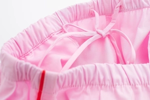 Vue détaillée du pantalon de sport rose avec taille élastique, cordon et rayures rouges