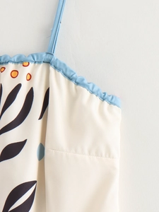 Detail of floral printed summer dress featuring blue ruffled neckline and thin spaghetti straps