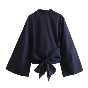 Detail of the oversized bow tie on the back of a navy blue poplin long-sleeve blouse