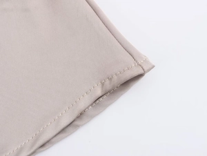 Dettaglio del tessuto satinato taupe con rifiniture di alta qualità a punto ago singolo