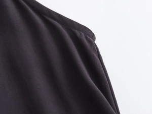 Close-up detail of the black V-neck midi dress showing seam work and twill texture