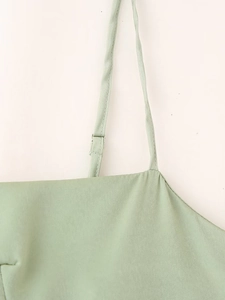 Détail des fines bretelles réglables sur une robe en satin vert clair ajustée