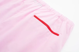 Détail du pantalon rose avec taille élastique et liseré rouge contrasté sur la poche