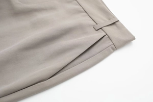 Detail view of khaki casual trousers showing waist belt loops and side pockets texture