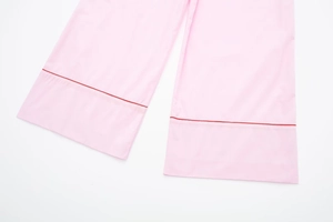 Détail du bas de pantalon de pyjama rose avec bordure rouge contrastée en popeline