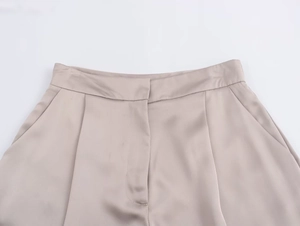 Dettaglio della vita di pantaloni in raso champagne con cuciture precise e tasche laterali