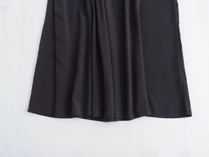 Detailed close-up showing the smooth hem and pleated fabric of a black midi dress