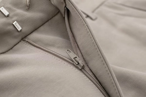 Detail of khaki trousers showing metal hook closure, smooth zipper and precise stitching