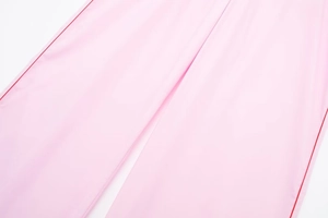Gros plan du pantalon en popeline rose montrant la texture du tissu et les coutures