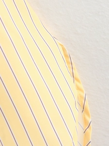 Detailed close-up of yellow and white striped shirt fabric with fine stitching quality