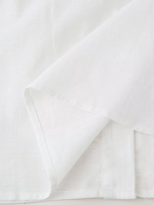 Detailed close-up showing the breathable linen fabric texture and hem stitching of the white shirt