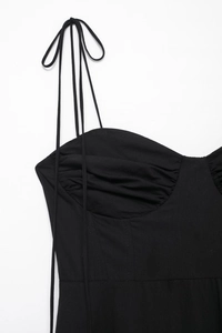 Detail of black poplin dress featuring thin straps and gathered pleated bodice design
