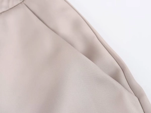 Dettaglio dei pantaloni in raso kaki che mostra la trama saia e la tasca laterale cucita