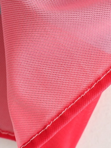 Detailed macro view of the breathable red mesh fabric and white stitching on a summer dress