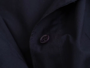 Detailed close-up of navy blue poplin shirt fabric featuring matching buttons and stitching