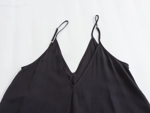 Detail of black V-neck dress featuring adjustable spaghetti straps and lightweight fabric