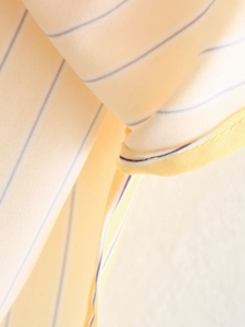 Detailed macro view of light yellow striped fabric with fine blue vertical patterns