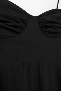 Close-up of ruched bodice and structured waist stitching on a black poplin dress