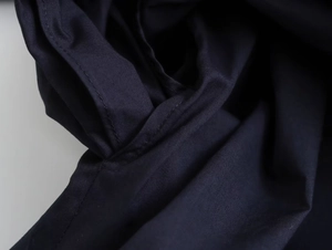 Detailed close-up showing precision stitching and texture on navy blue poplin fabric shirt