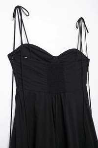 Detail view of black poplin dress with smocked back panel and delicate tie straps