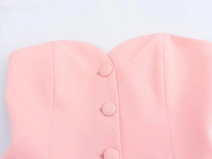 Dettaglio dello scollo a cuore rosa con bottoni in tessuto sul top a fascia elegante