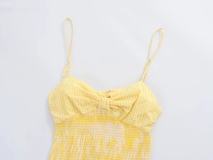 Detail of summer gingham dress featuring a yellow V-neck bow and smocked elastic bodice