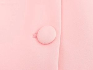Vista macro dettagliata di un bottone rivestito in tessuto rosa e di un'asola cucita