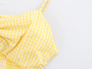 Detail of yellow gingham top featuring smocked bodice and thin spaghetti shoulder straps