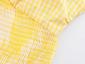 Detailed macro view of yellow and white gingham fabric with smocking craft and elastic texture