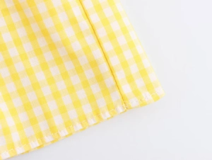Detail view showing yellow gingham fabric texture and precise double stitching on the dress