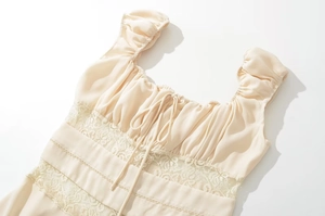 Detailed view of cream lace hollow-out stitching and smocked puff sleeves on summer dress