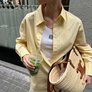 Women's casual striped long sleeve shirt with ribbed white vest and straw tote bag outfit