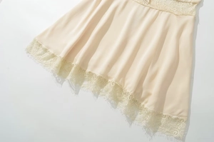 Close-up of champagne satin fabric with intricate floral eyelash lace hem detail