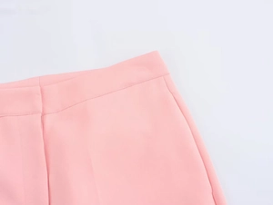 Dettaglio dei pantaloni rosa chiaro a vita alta con tessuto liscio e cuciture fini