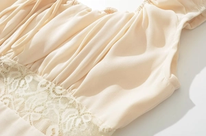 Close-up of beige summer dress showing pleated chiffon texture and lace stitching details