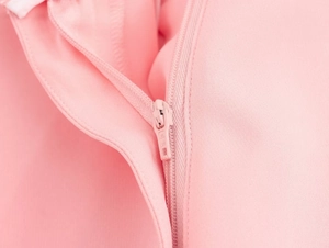 Dettaglio della cerniera YKK su un indumento rosa testurizzato con cuciture rifinite e precise
