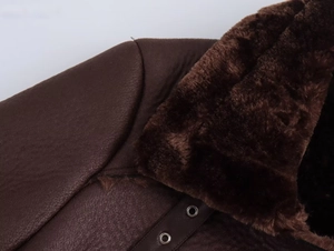 Gros plan d'une veste en simili cuir marron avec col en fourrure et détails d'oeillets argentés
