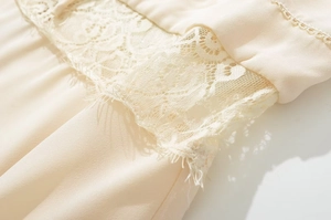 Close-up of elegant apricot lace patchwork and delicate eyelash trim on summer dress