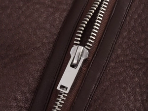 Gros plan d'une veste en cuir marron foncé avec texture litchi et fermeture éclair argentée