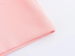 Dettaglio macro dell'orlo dei pantaloni rosa con cuciture rifinite e trama del tessuto